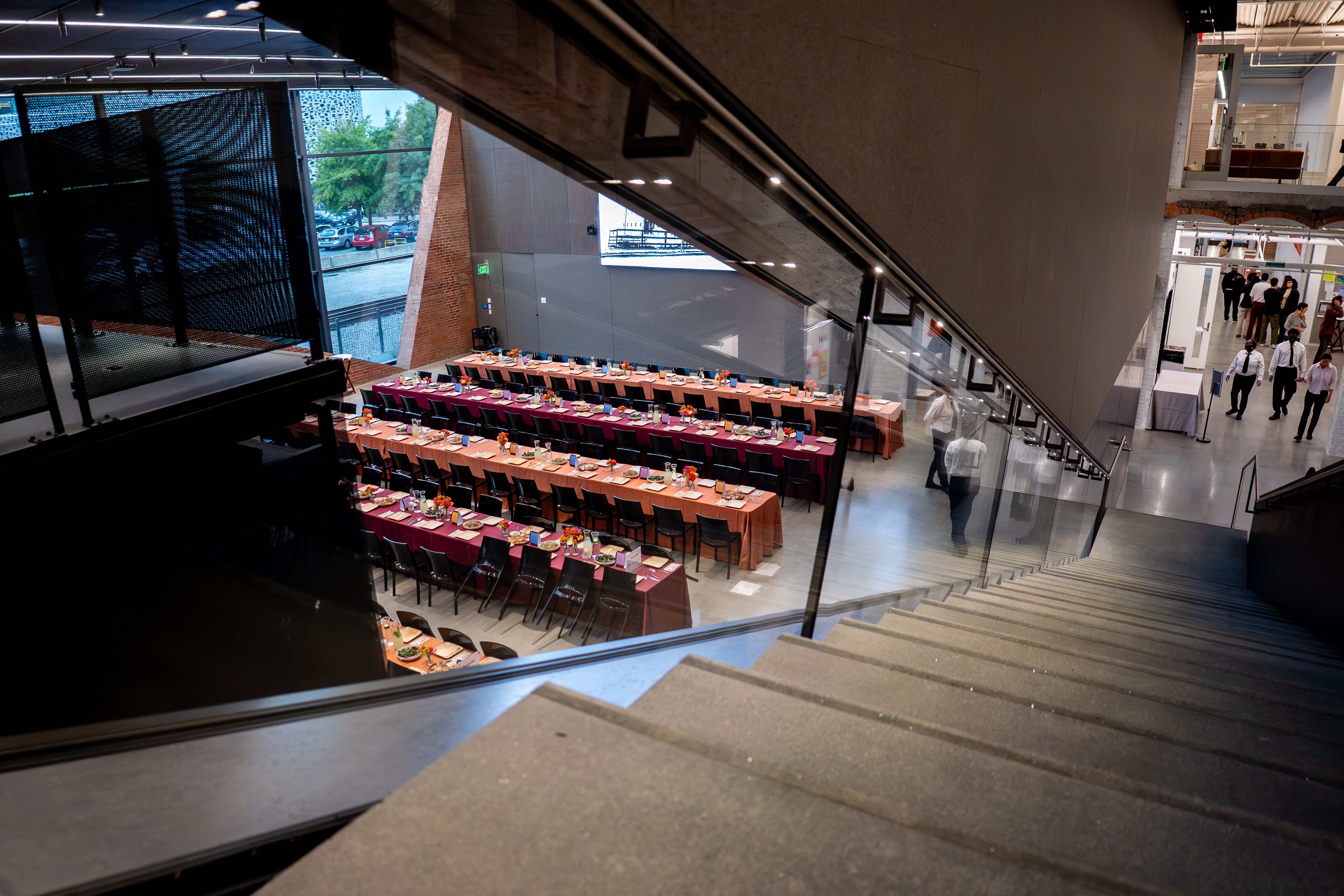 Long tables set up in the MET Warehouse auditorium with orange and burgundy tablecloth, viewed from the stairs