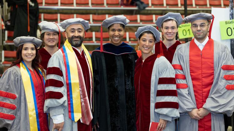 A group of PHD graduates and faculty pose for photo at procession lineup 