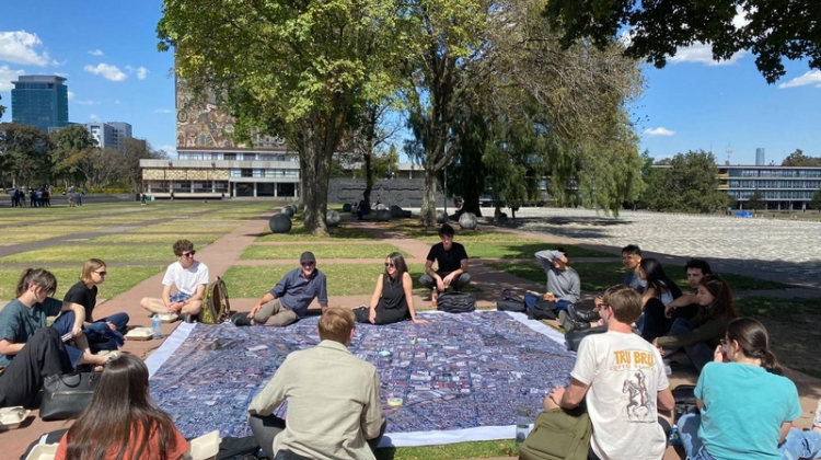 People sitting in a park around a picnic blanket