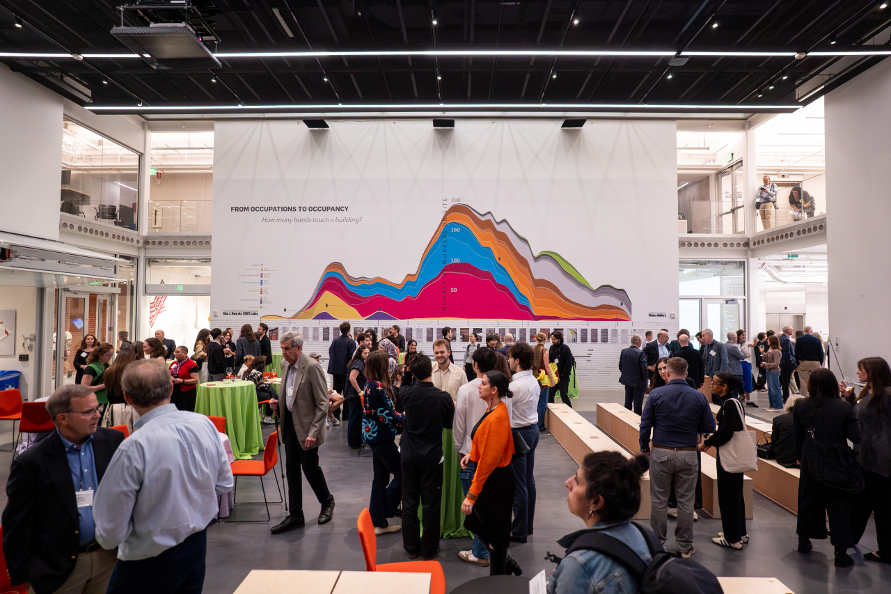 Guests gather in the MET Warehouse during its dedication ceremony, with the “From Occupations to Occupancy” exhibition displayed across a large gallery wall.