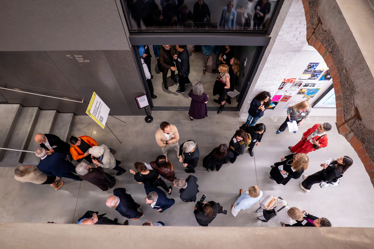 Overhead view of guests mingling in the atrium of MIT’s MET Warehouse during the building’s dedication ceremony.