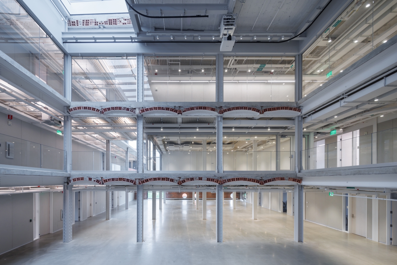 Interior of the renovated MET Warehouse at MIT, showing exposed steel framing, brick arches, and open multi-level spaces.
