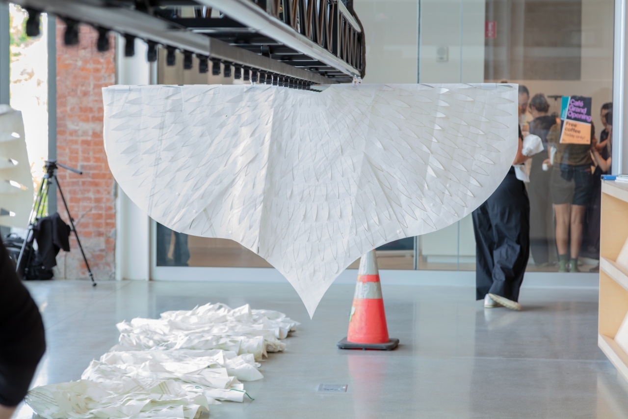 Work by Azra Aksamija, Students install a suspended textile artwork made of layered white fabric panels inside MIT’s Metropolitan Storage Warehouse.