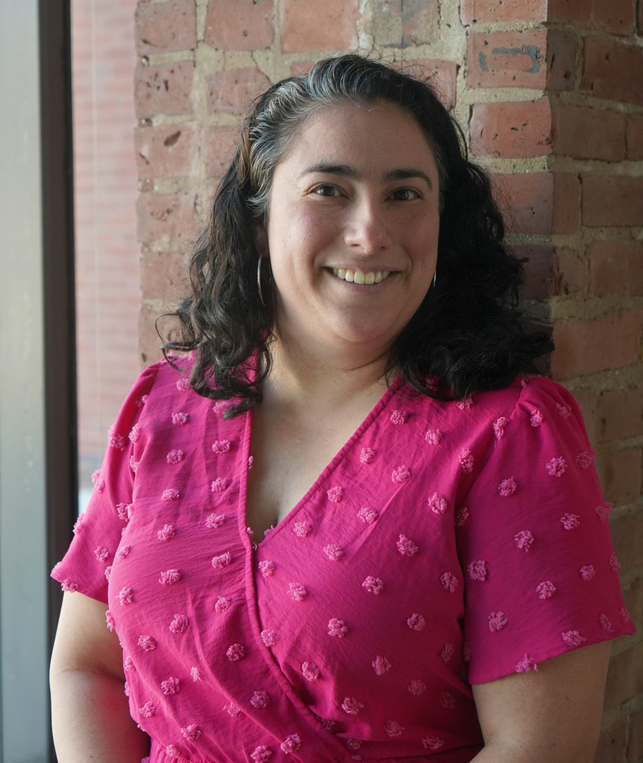Headshot of Monica Orta wearing a pink dress
